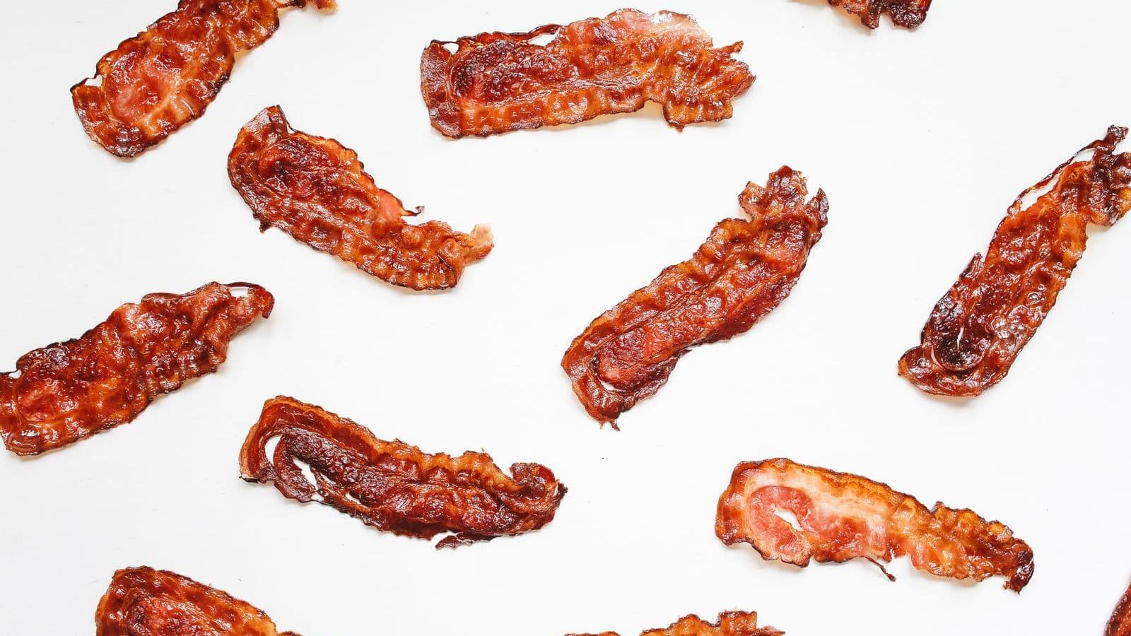 Crispy bacon strips on a white surface - Can Dogs Eat Bacon? Why It Is a Poor Choice